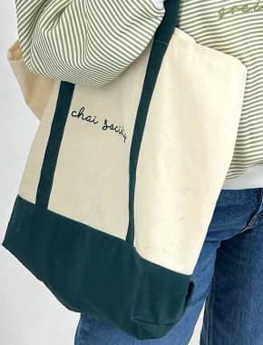Close-up of the tote with chai society stitched in script